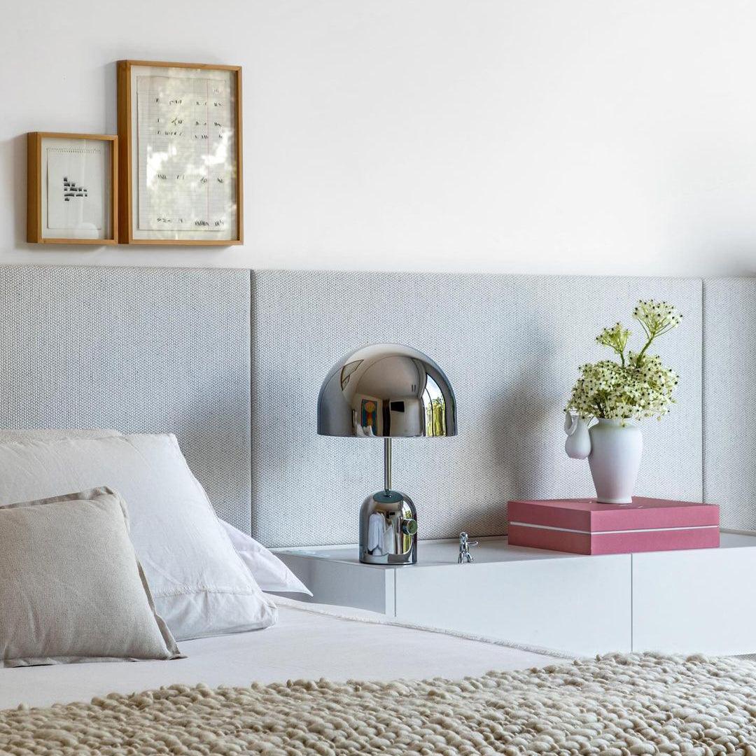 Modern bedroom with bed, lamp, and decorative items on a shelf.