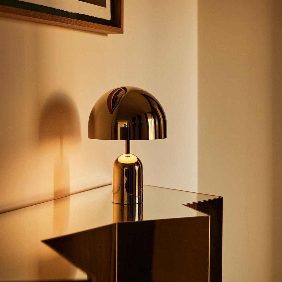 Gold table lamp on a reflective surface with a neutral background