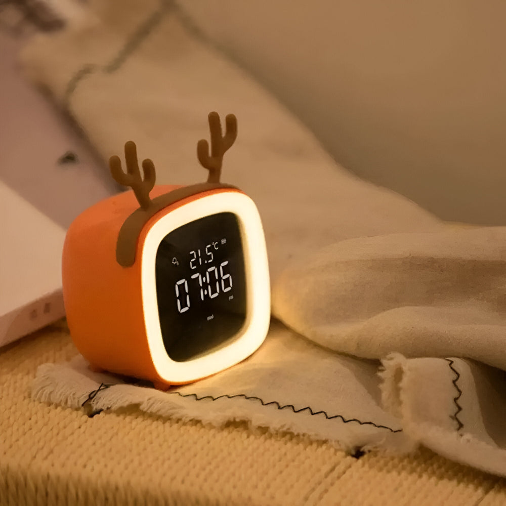 Cute orange clock with deer antlers on a soft surface