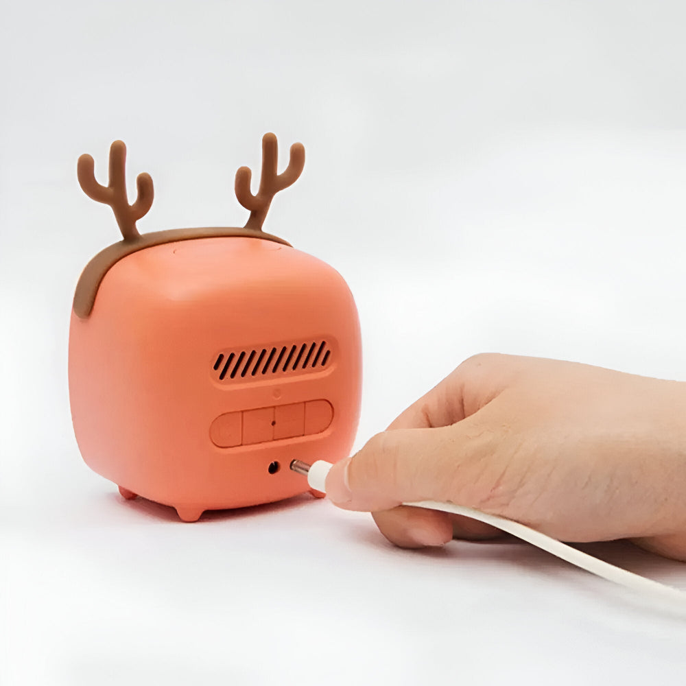 Small orange device with reindeer antlers being charged by a hand on a white background