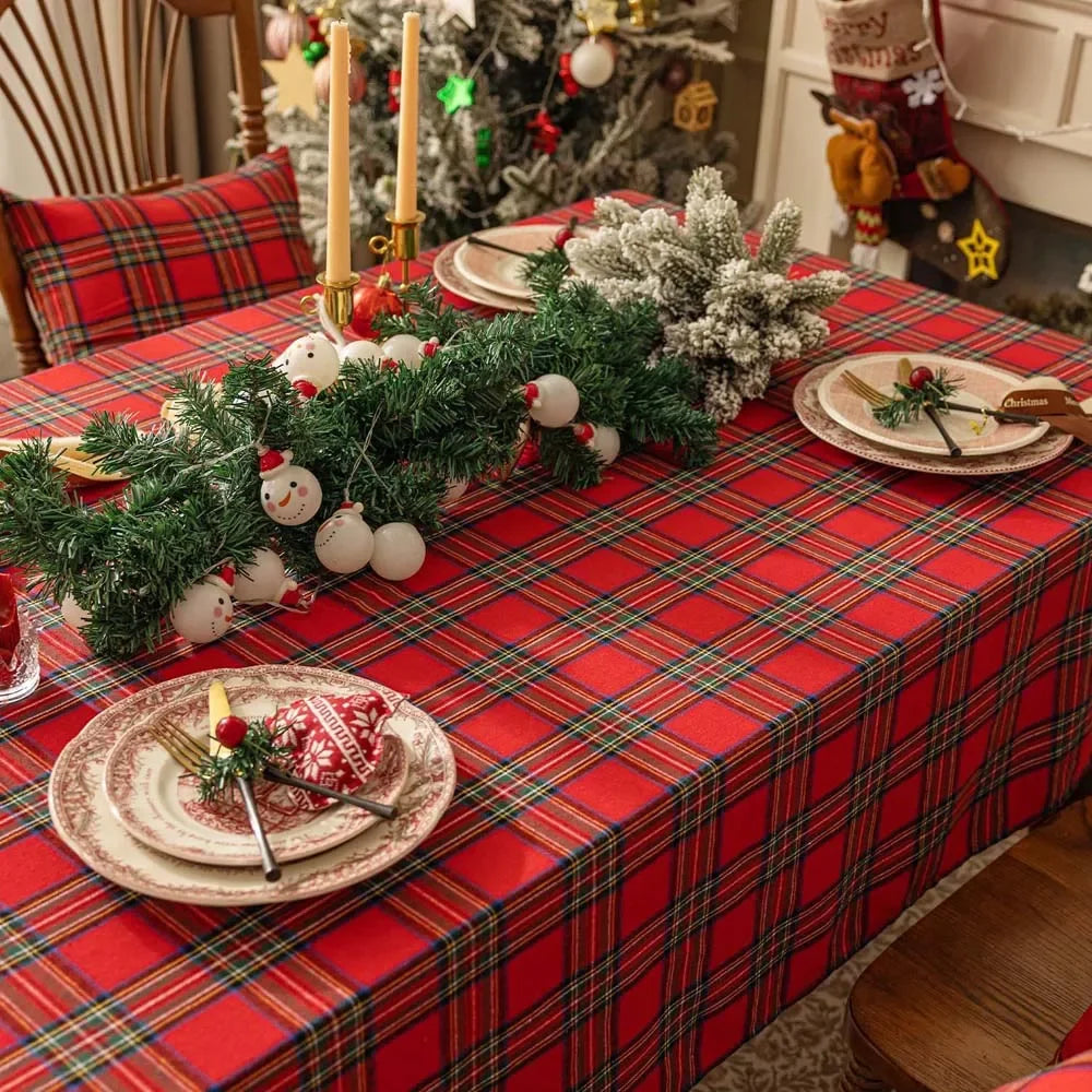 Decorated Christmas table with red plaid tablecloth, greenery, and festive decorations.