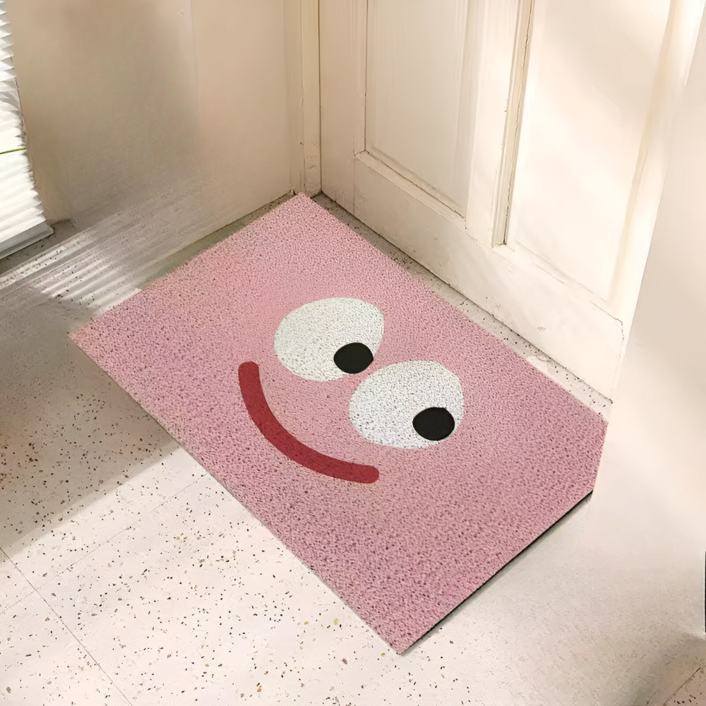 Pink doormat with a smiley face design on a tiled floor.