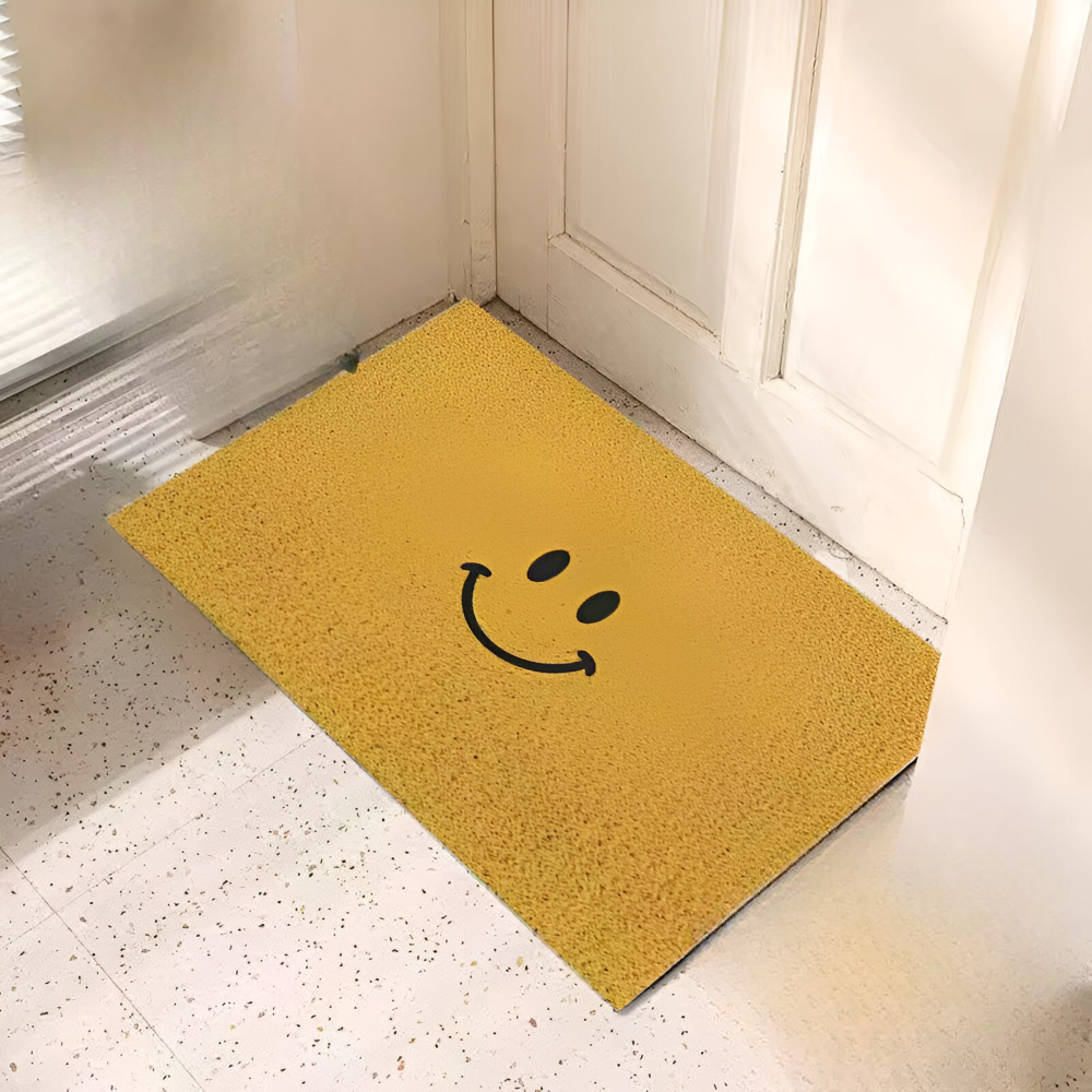 Yellow doormat with a smiley face design on a floor.