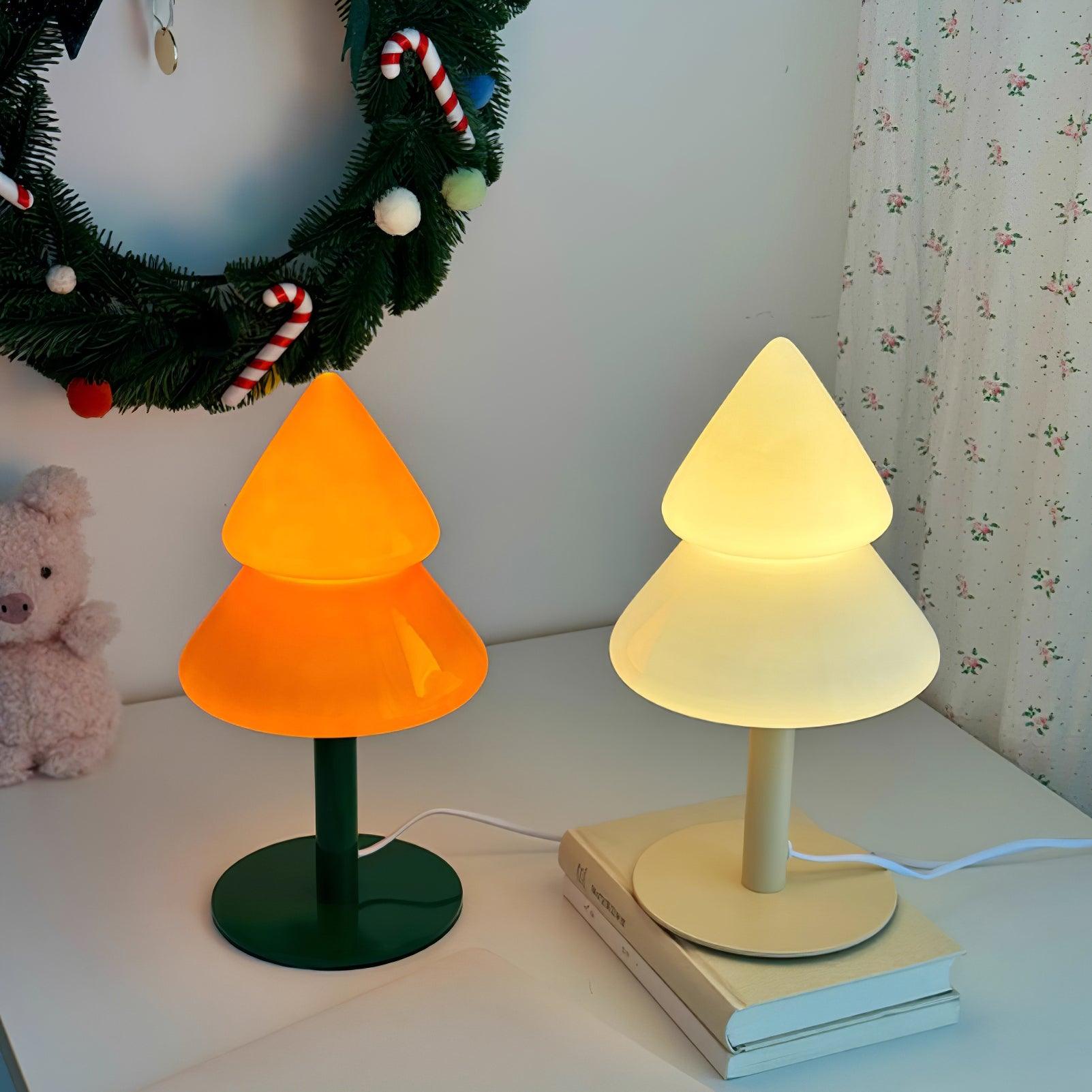 Two tree-shaped lamps, one orange and one beige, on a surface with a Christmas wreath in the background.