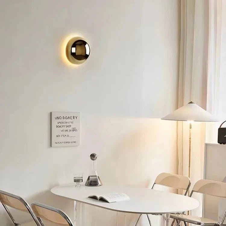 Modern interior with a round wall light fixture, dining table, and chairs.
