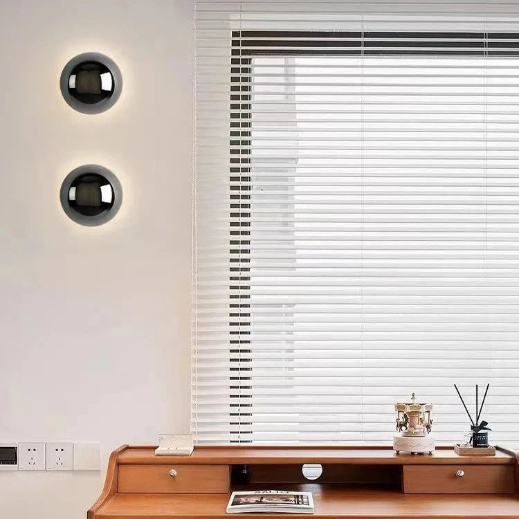 Modern interior with a window featuring white blinds, a wooden desk, and decorative items.