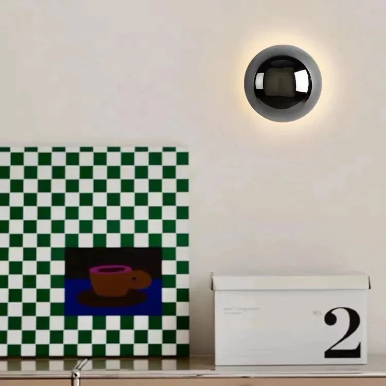 Modern wall light fixture on a white wall with a checkered picture and calendar below.