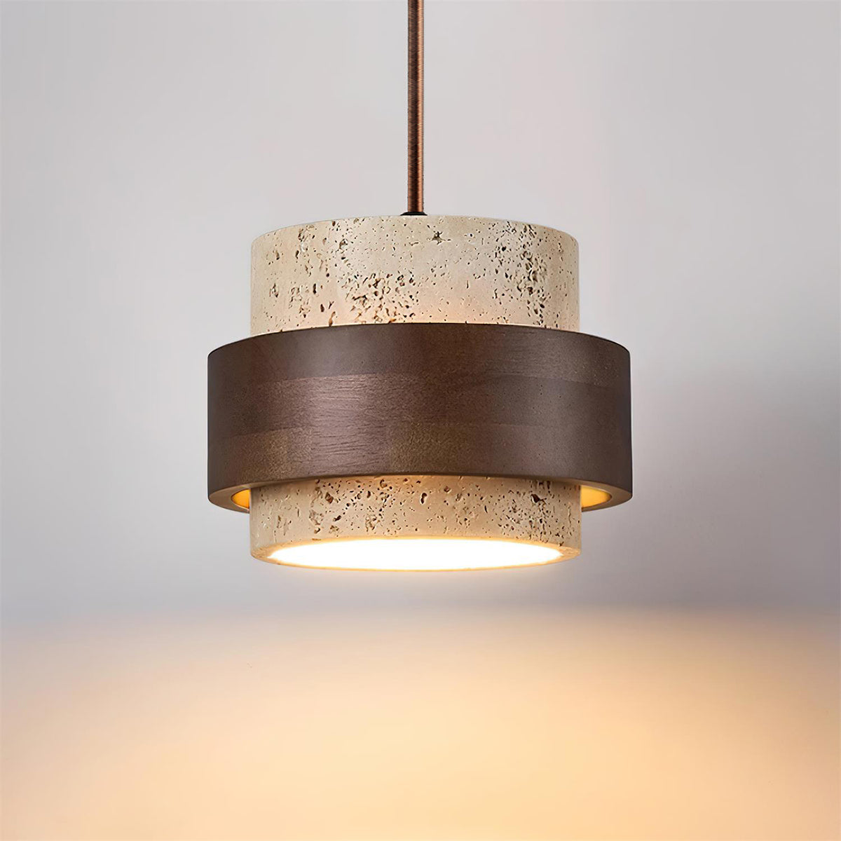 Pendant light with concrete-like finish and bronze accents on a neutral background