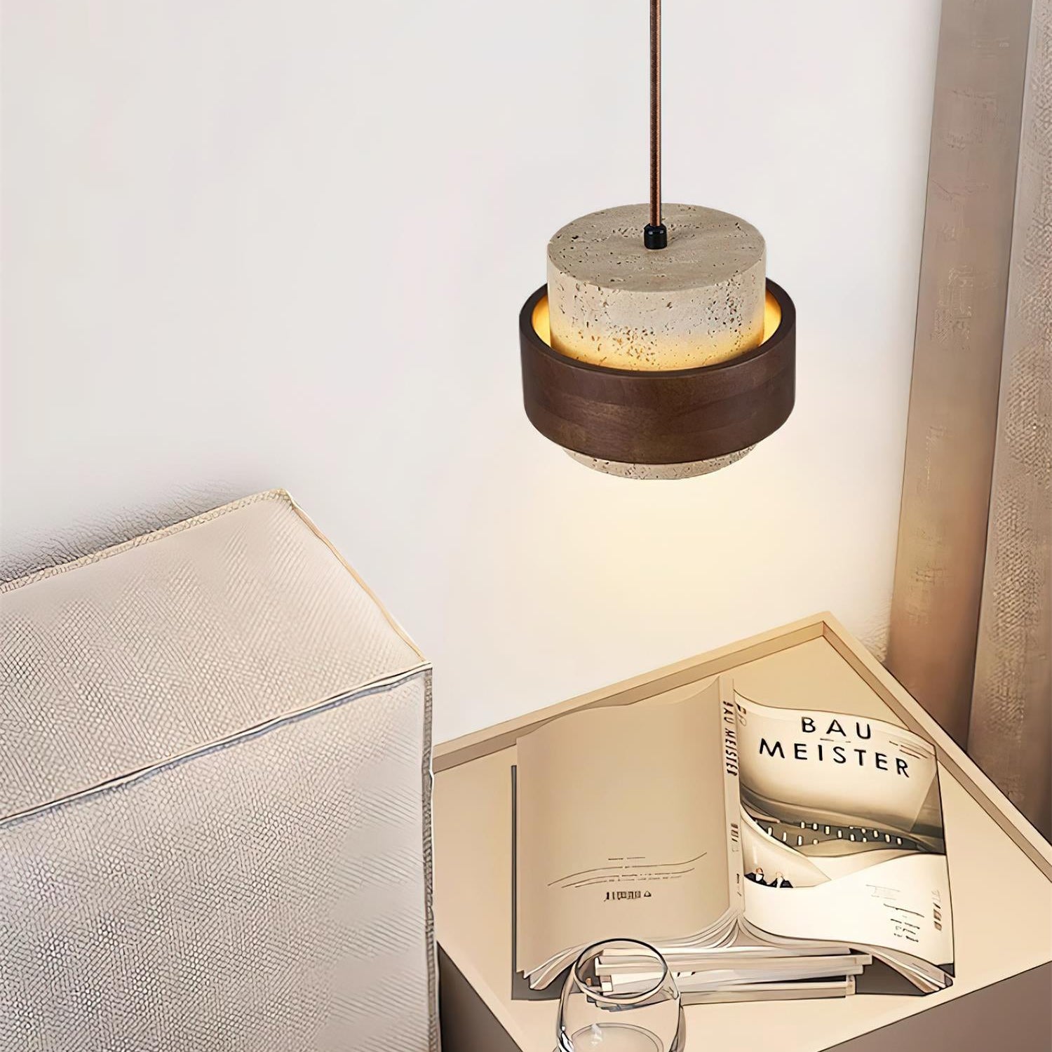 Modern pendant light above a nightstand with a magazine and glass.