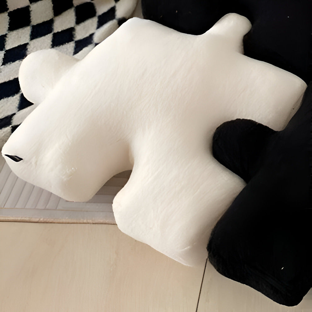 White bear-shaped pillow on a wooden surface with a checkered fabric background
