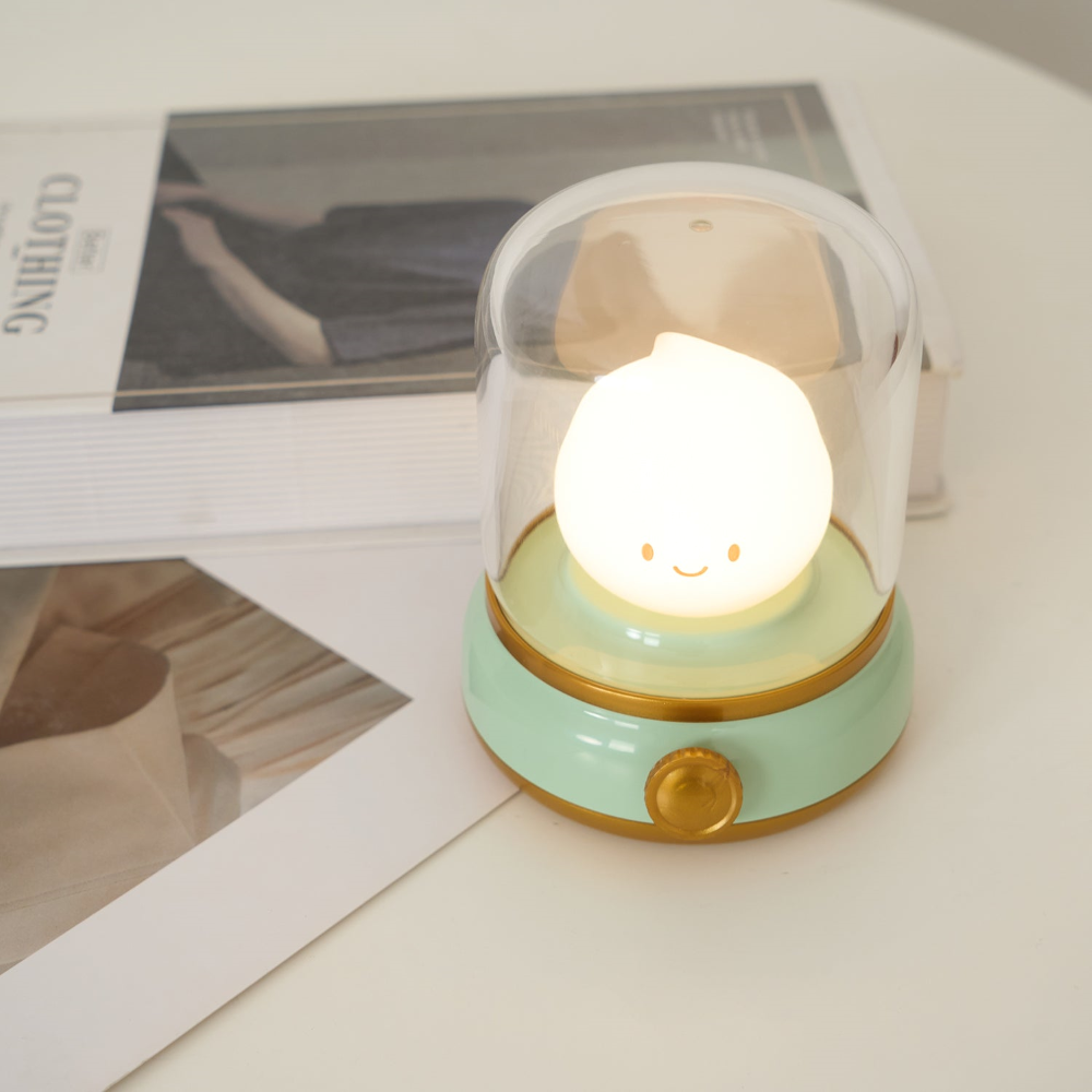 Small round night light with a smiling face on a surface with magazines in the background