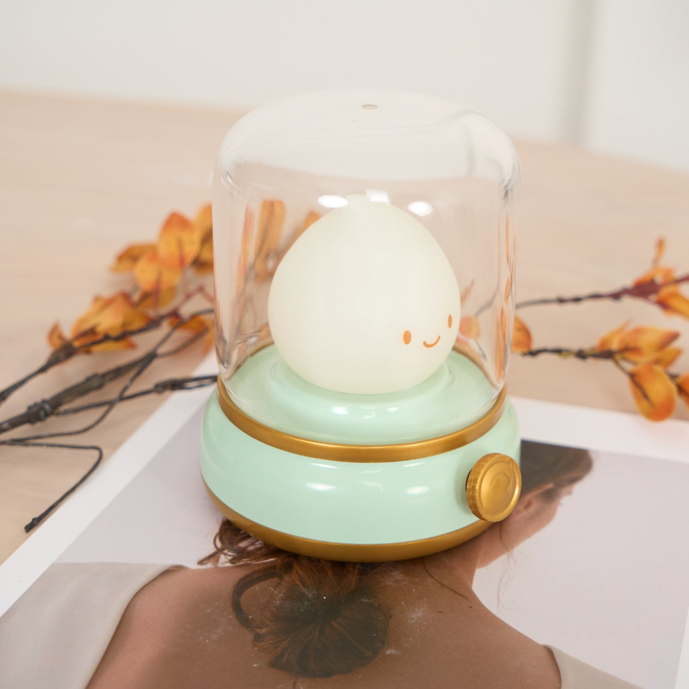 Person receiving a head massage with a novelty lamp on a white surface.