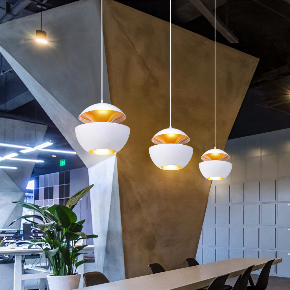 Modern pendant lights hanging in a stylish office setting with a geometric ceiling design.