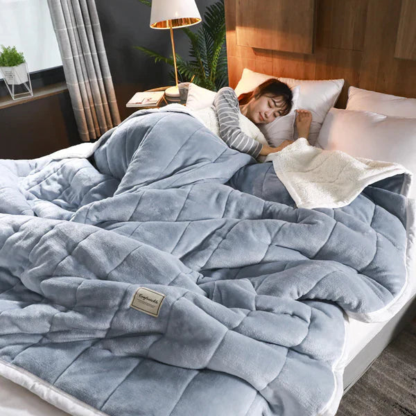Person lying in bed under a weighted blanket with a cozy bedroom setting.