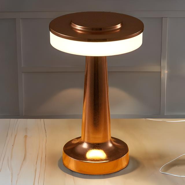 Copper-colored table lamp on a wooden surface with a neutral background