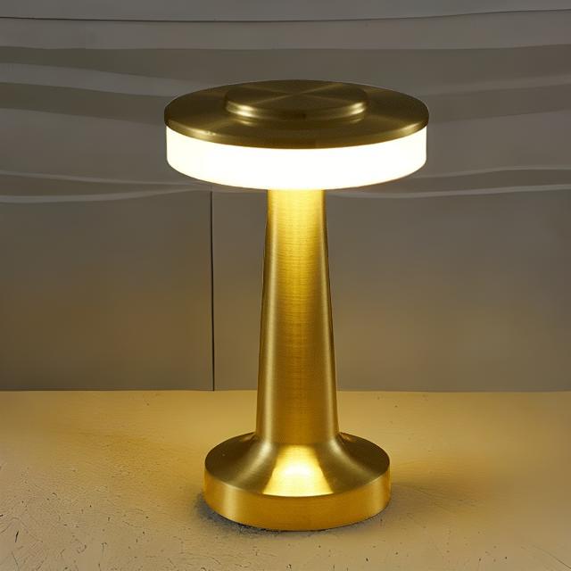 Gold-colored lamp with a cylindrical base and round top on a neutral background
