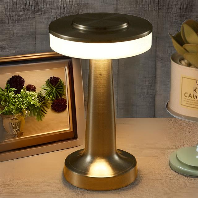 Gold table lamp on a wooden surface with decorative items in the background