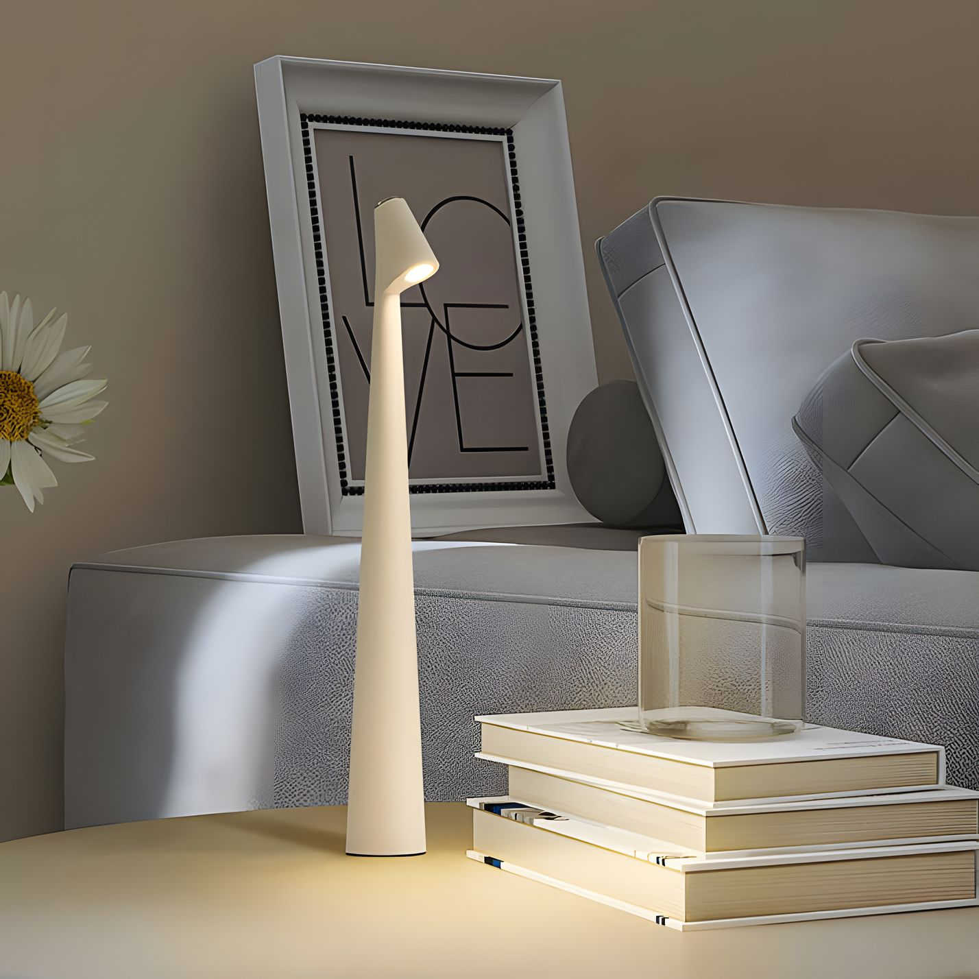 White lamp on a table with books and a framed picture in the background