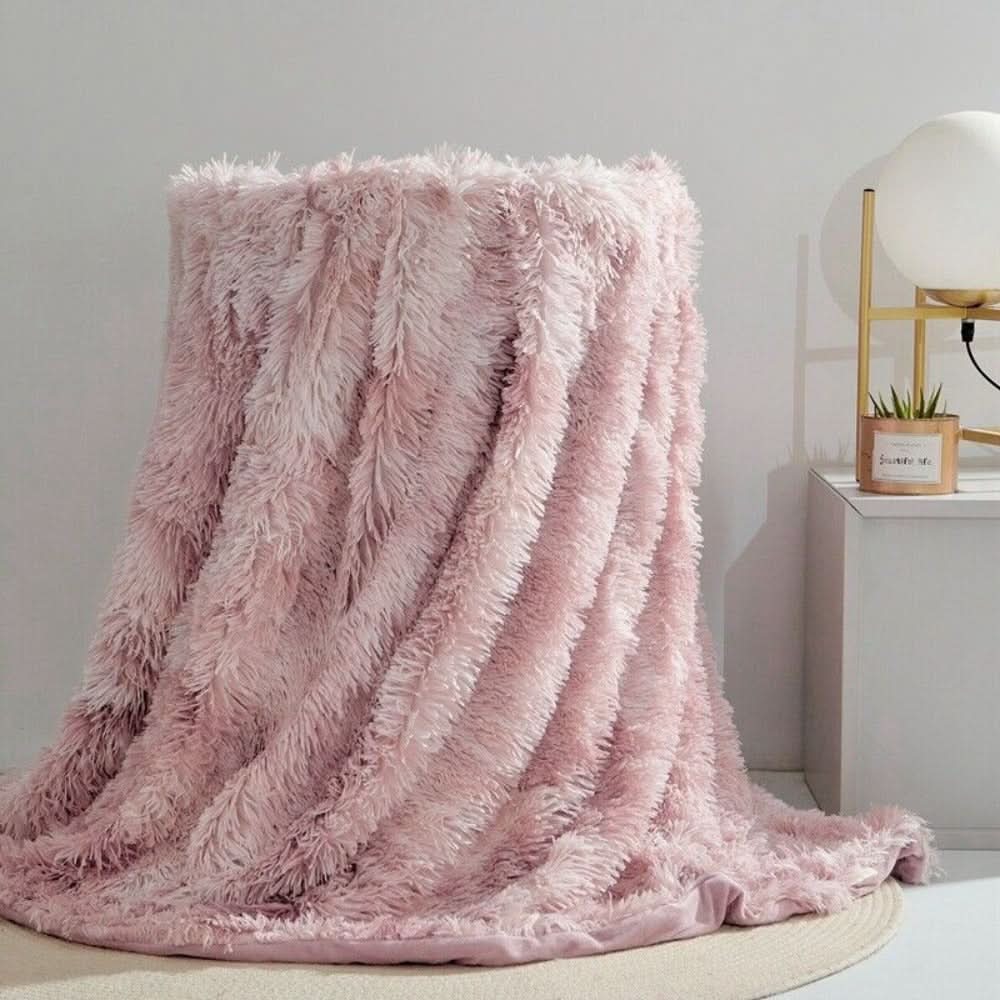 Pink fluffy blanket draped over a chair in a room with a lamp and plant in the background.