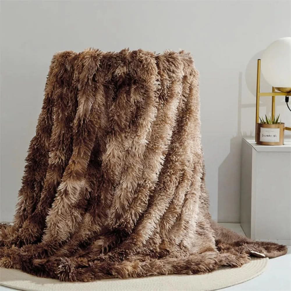 Brown fluffy blanket draped over a chair in a room with a white wall and small table.