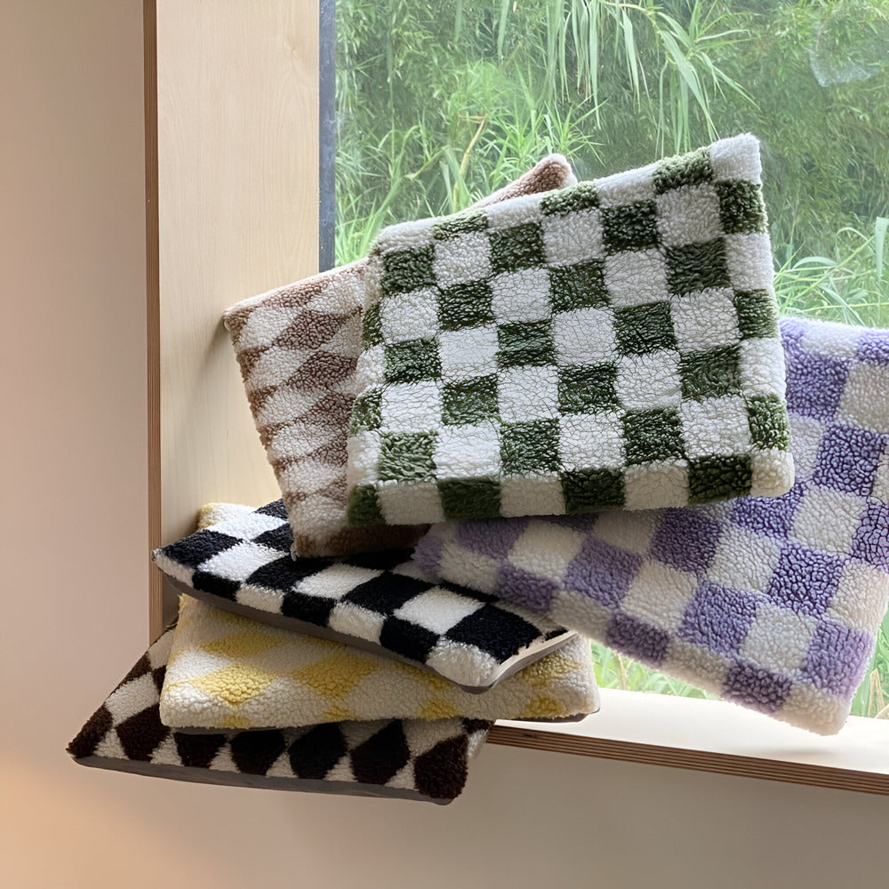 Stack of patterned cushions on a windowsill with a view of greenery outside.