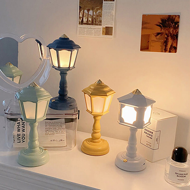 Four decorative lamps in different colors on a surface with a mirror and other items in the background.