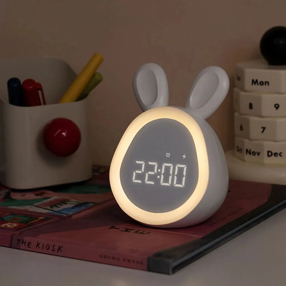 White rabbit-shaped clock with digital display on a surface with books and stationery items.