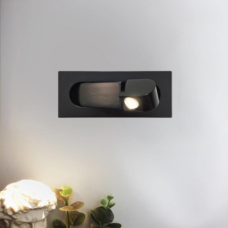Modern black wall-mounted light fixture on a white wall with decorative elements at the bottom.