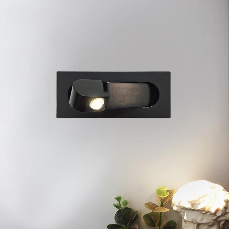 Black recessed wall light fixture on a white wall with a soft glow.