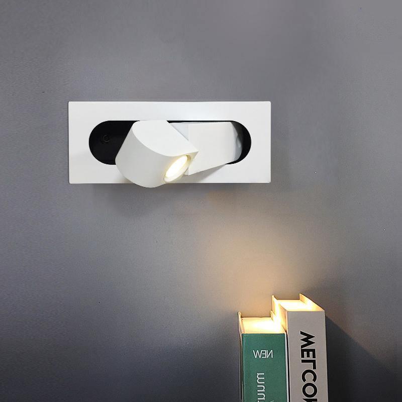 Modern wall-mounted light fixture on a gray wall with books below.