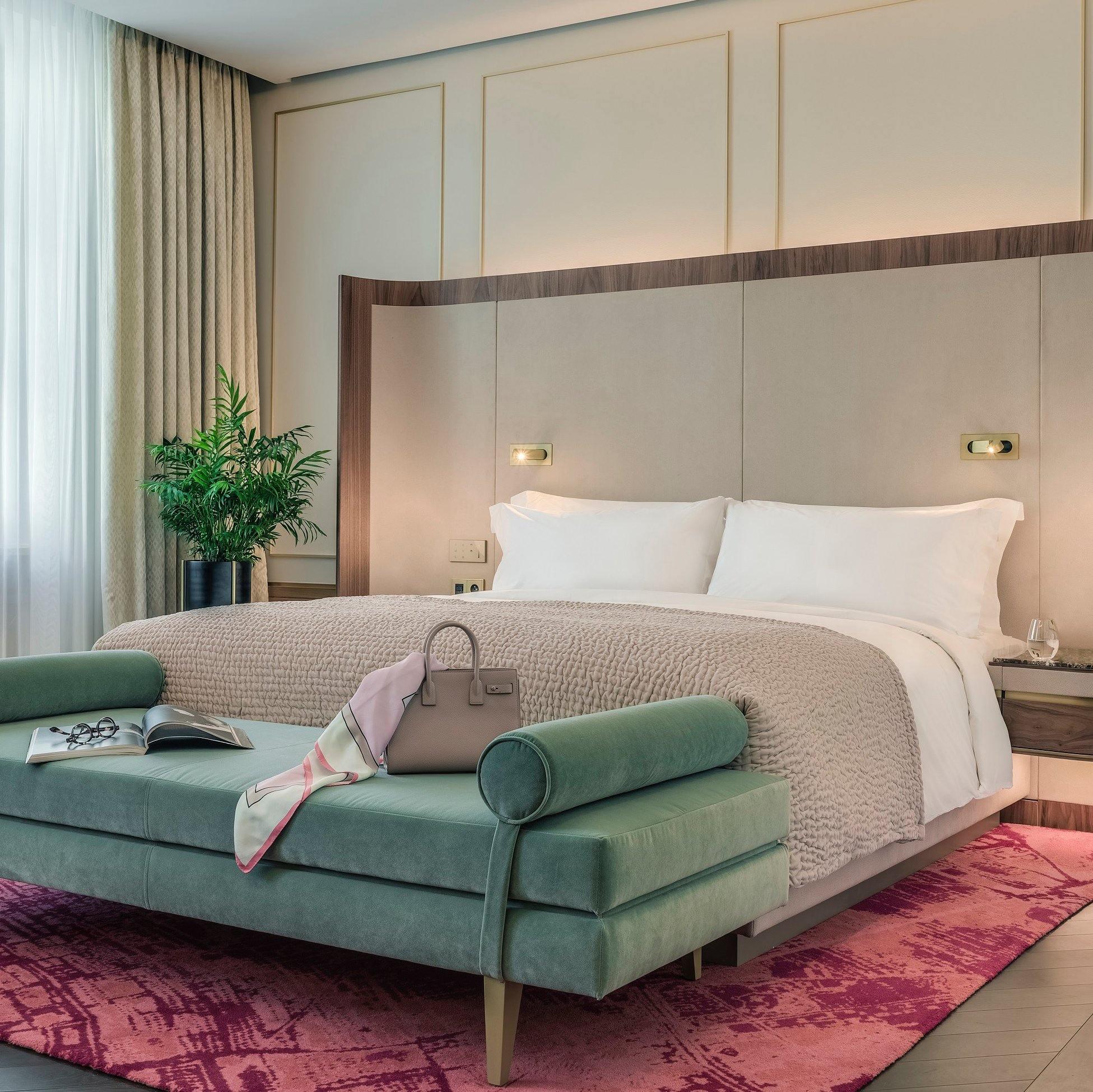 Modern bedroom with a bed, green sofa, and pink rug.