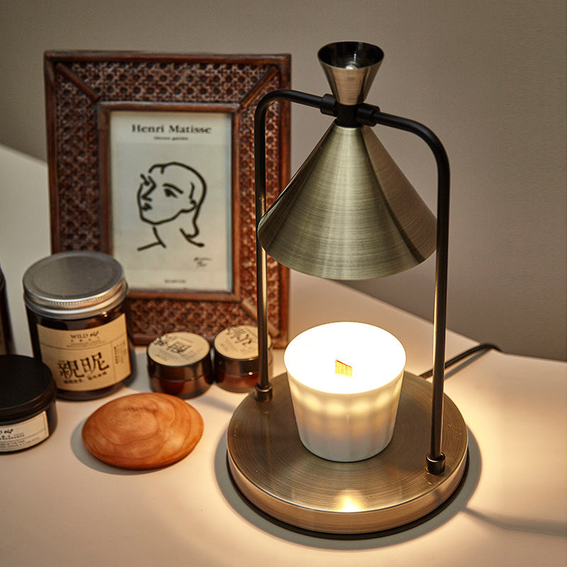 Brass lamp with a candle on a table next to a framed picture and jars.