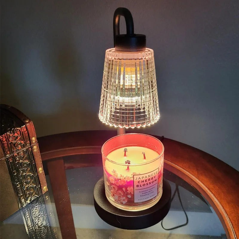 Candle with a decorative lamp on top, placed on a reflective surface.