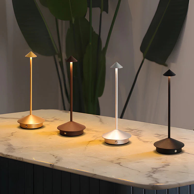 Four small lamps on a marble surface with a plant in the background