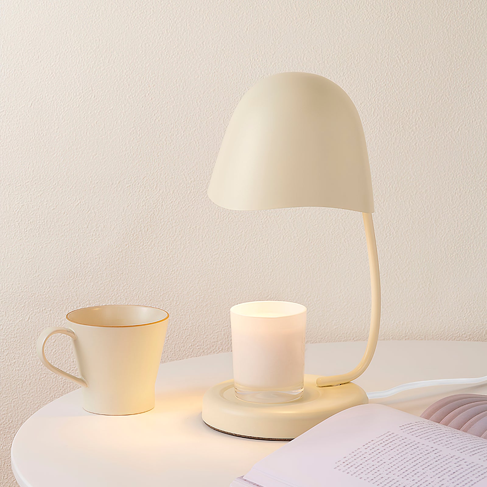 Cream-colored table lamp and mug on a nightstand against a light wall.