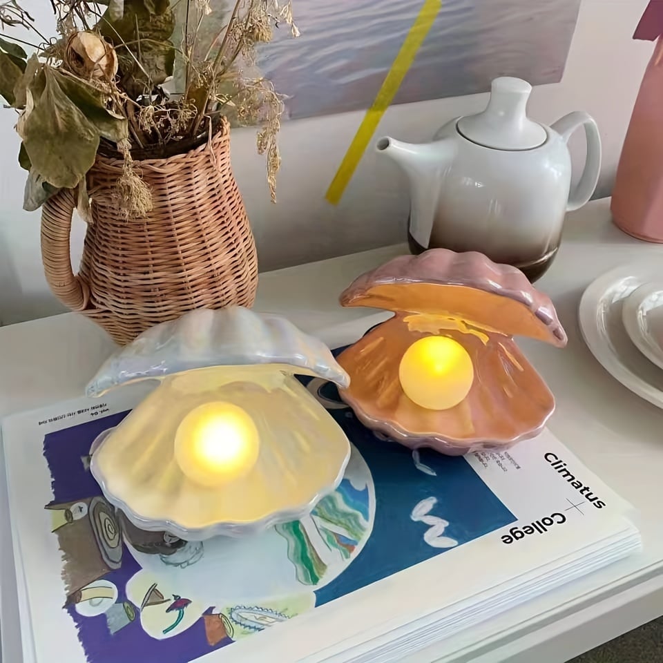 Decorative shell-shaped candle holders with candles on a magazine