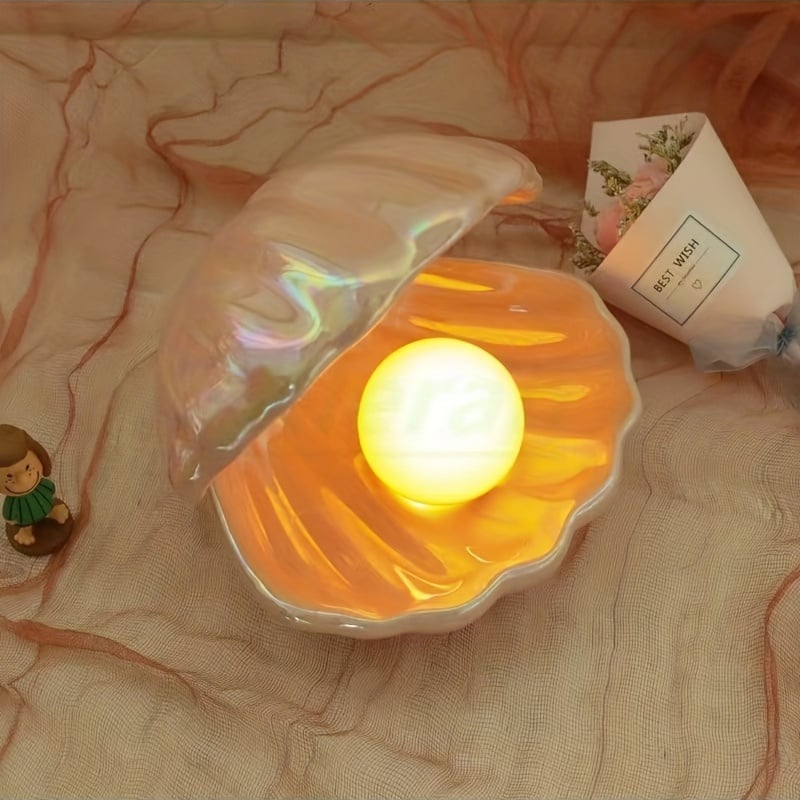 Shell-shaped night light with a glowing interior on a textured surface