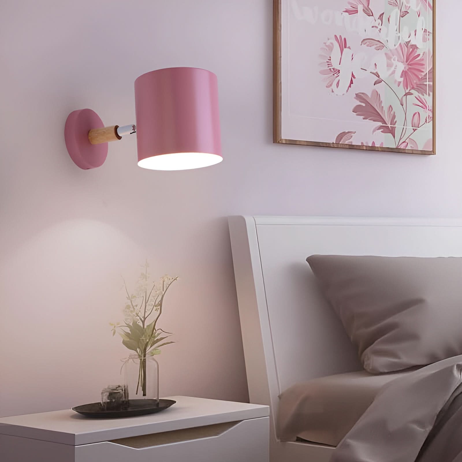 Pink wall lamp on a white nightstand with a floral painting in the background