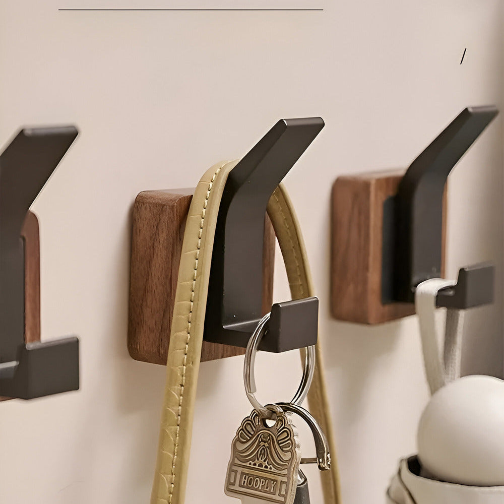 Wall-mounted hooks holding a dog leash and keys against a neutral wall.