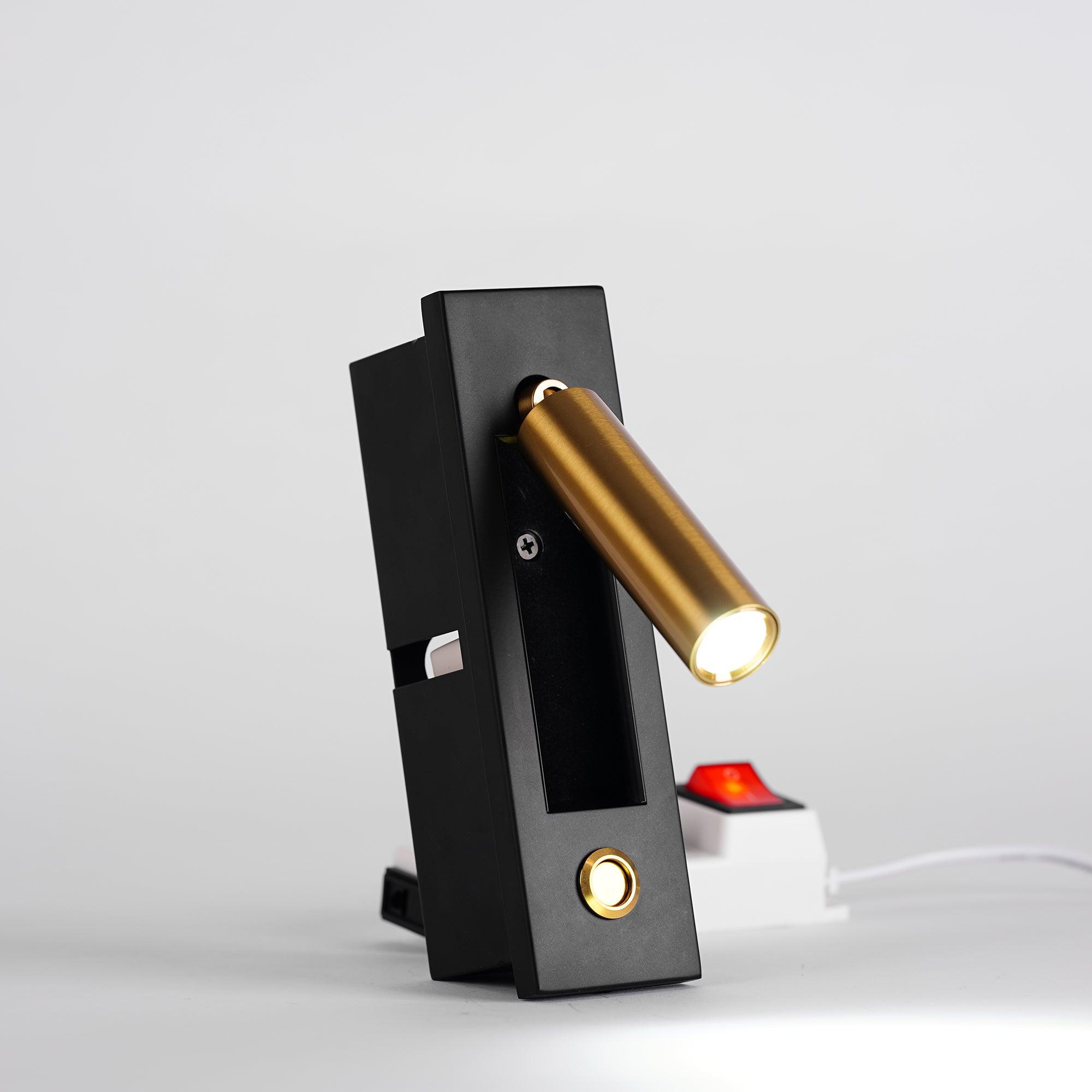 Modern wall-mounted light fixture with black base and gold cylindrical lamp on a white background