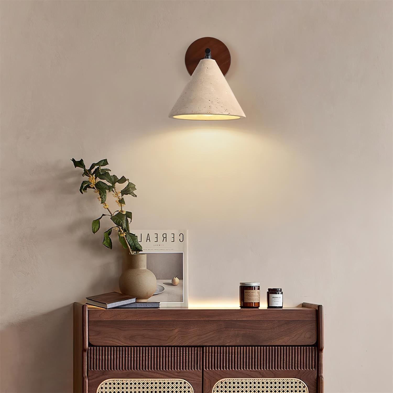Wall-mounted light fixture casting a warm glow on a wooden console table with decorative items.