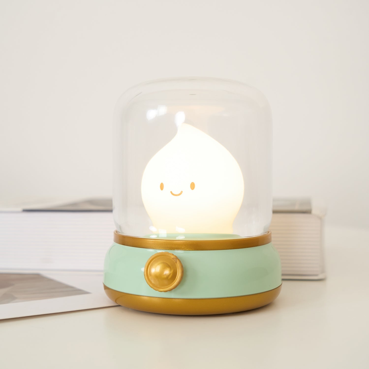 Cute night light with a smiling face inside a glass dome on a white surface.