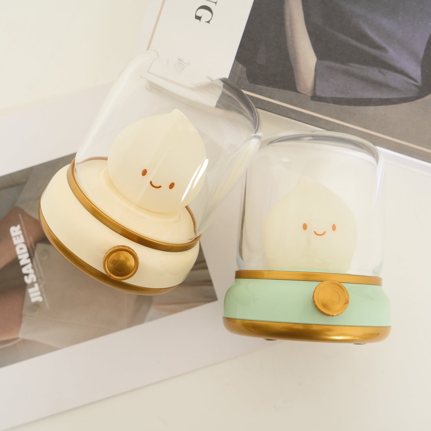 Two cute lamp-shaped night lights with smiling faces on a magazine background.