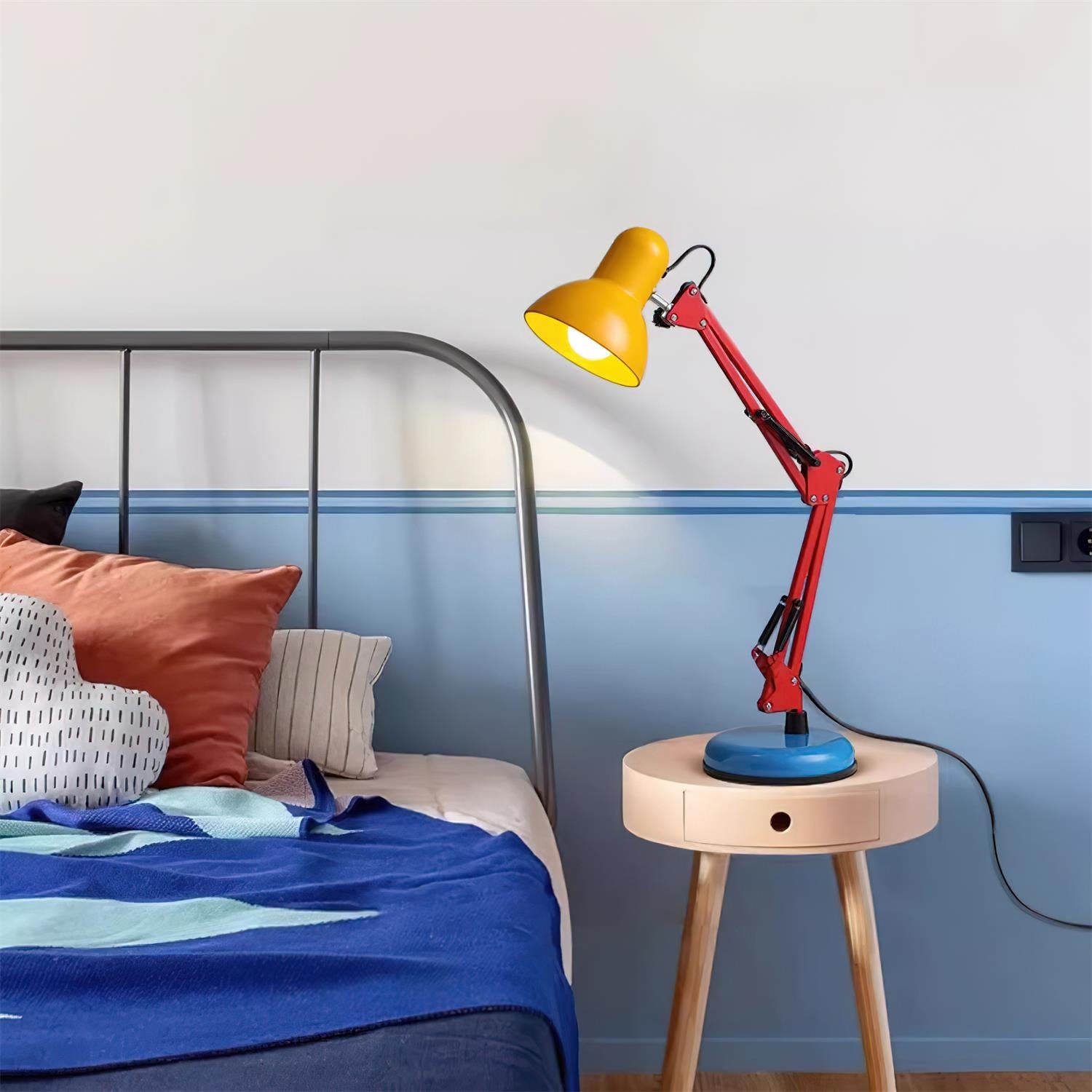 Colorful lamp on a wooden side table next to a bed with pillows.