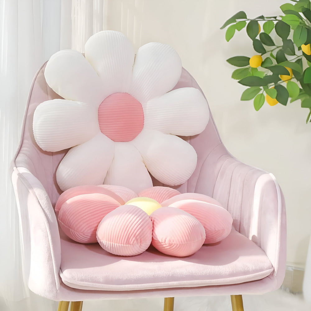 Flower-shaped cushion on a pink chair with a plant in the background