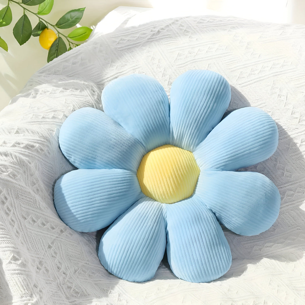 Blue flower-shaped pillow with a yellow center on a textured surface.
