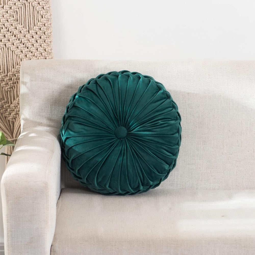 Teal round pillow on a beige sofa with a neutral background