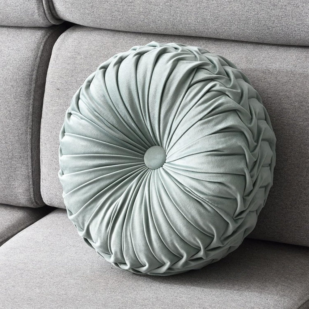 Round pleated cushion on a gray sofa