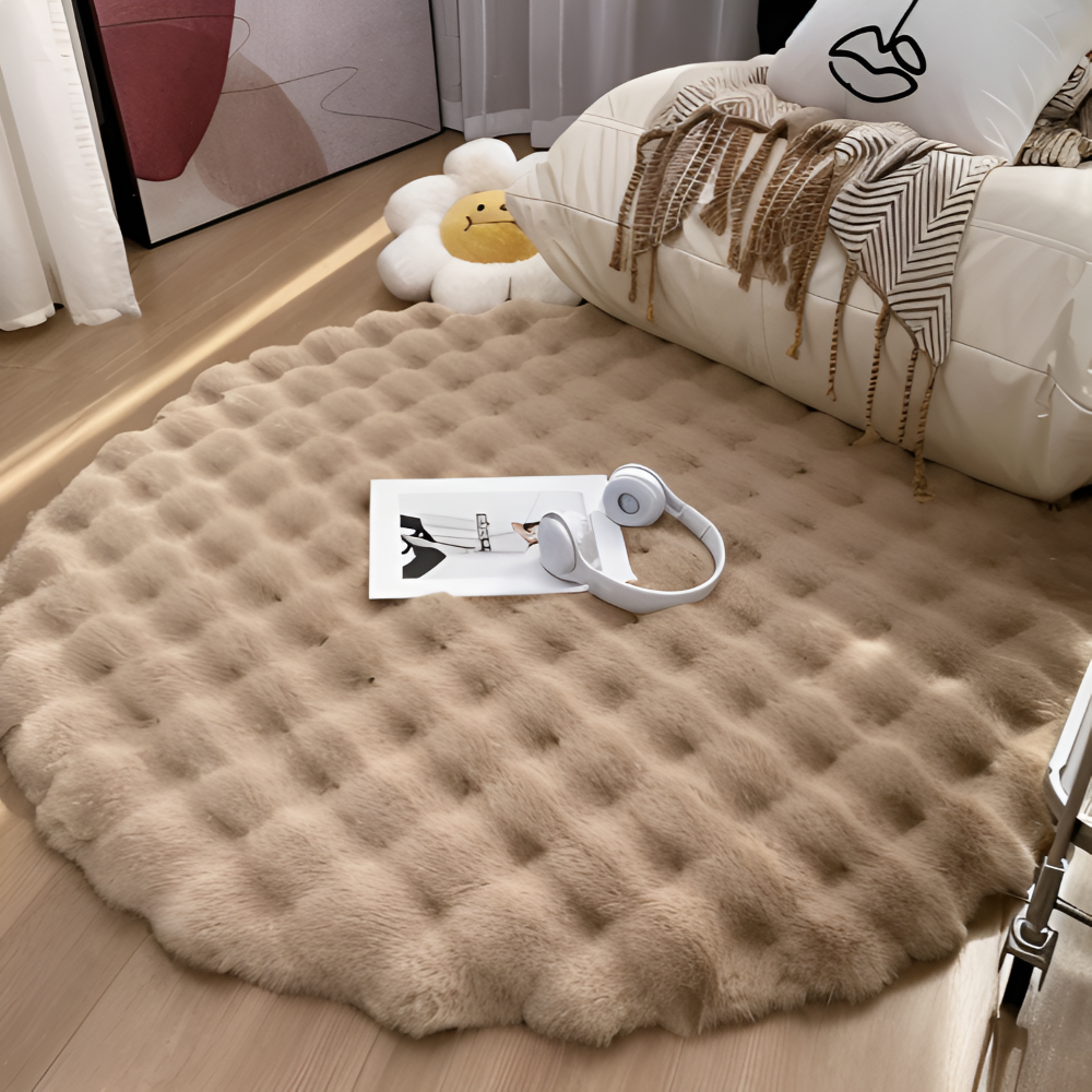 Round beige fur rug on a wooden floor with a sofa and decorative items in the background.