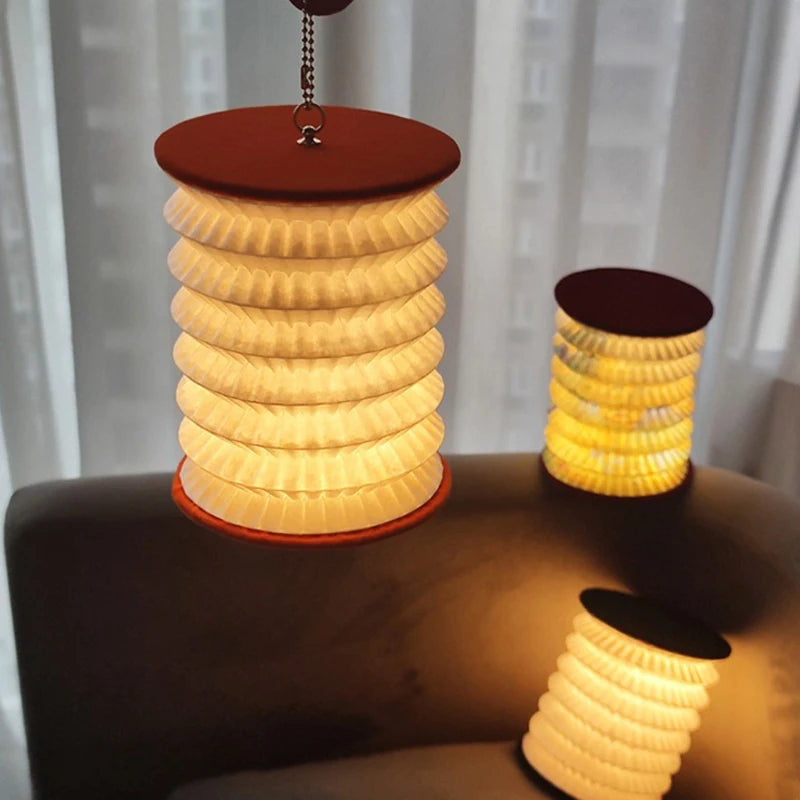 Set of three cylindrical lamps with ribbed design on a surface, with a blurred curtain background.